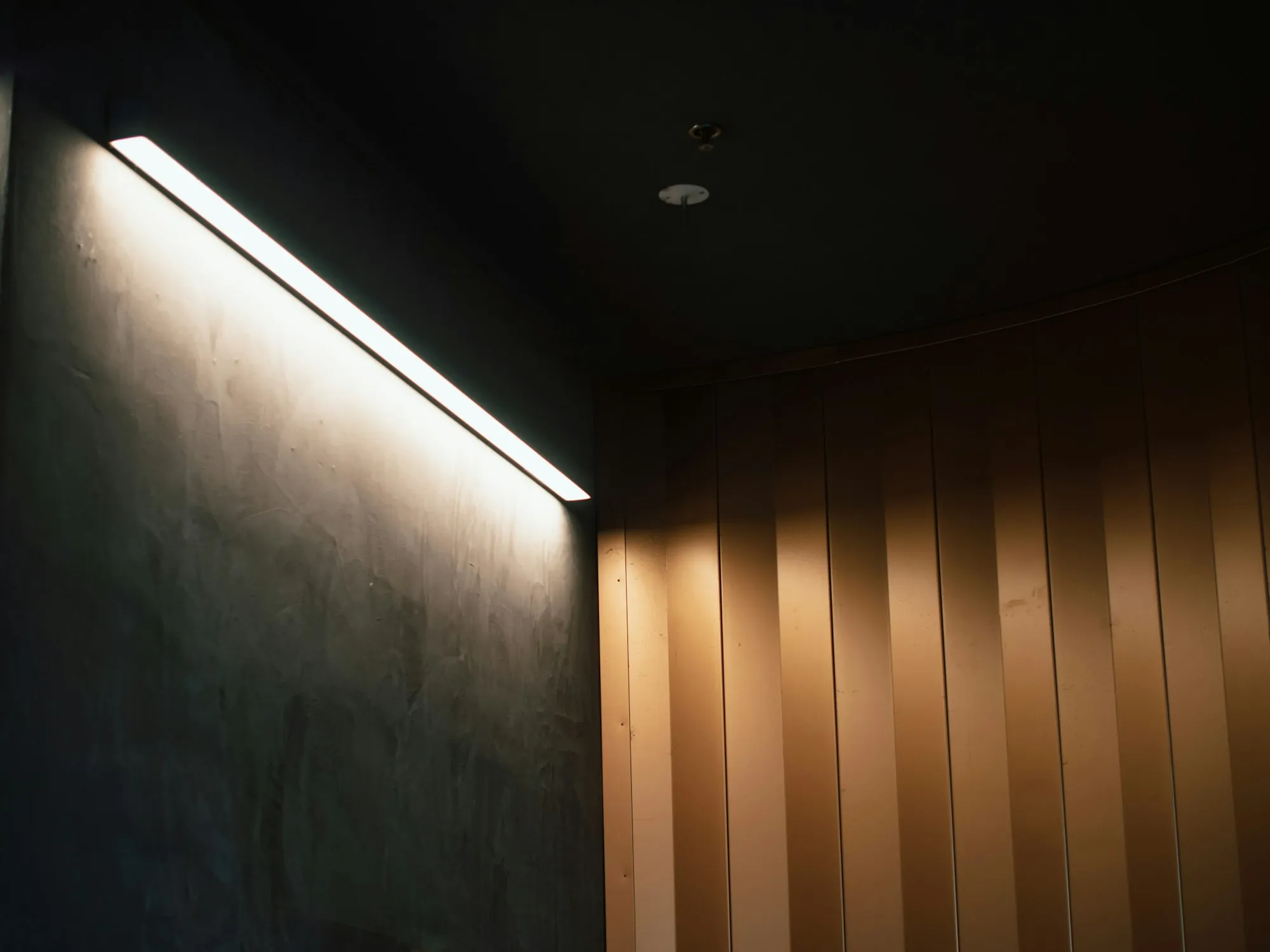 A linear light fixture casting soft light along a dark wall