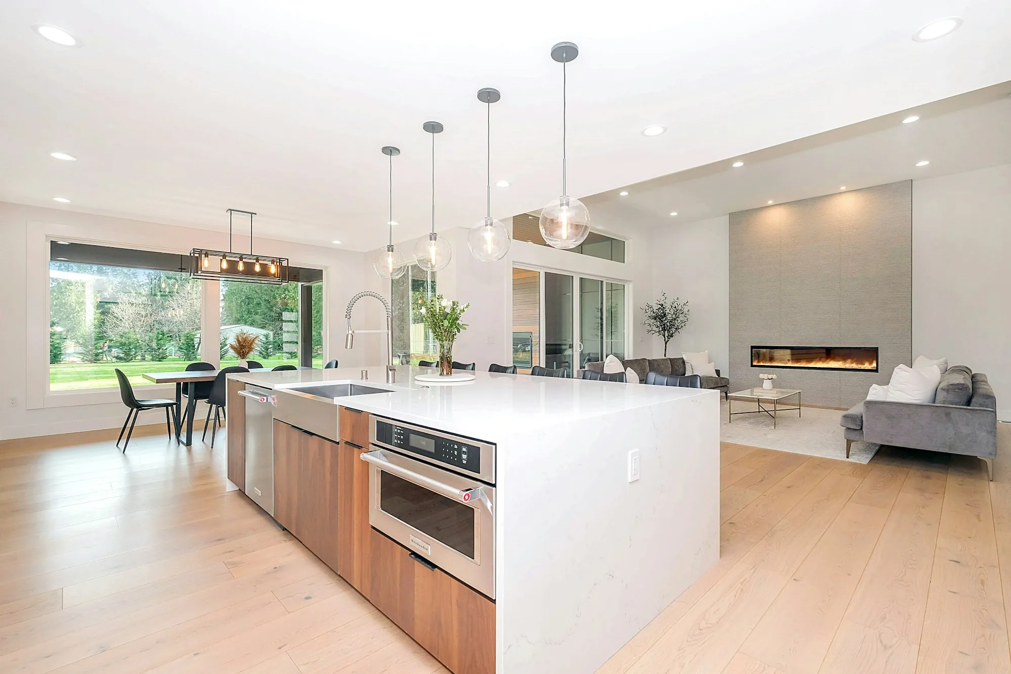 An open-plan living space lit by recessed ceiling lights and pendants