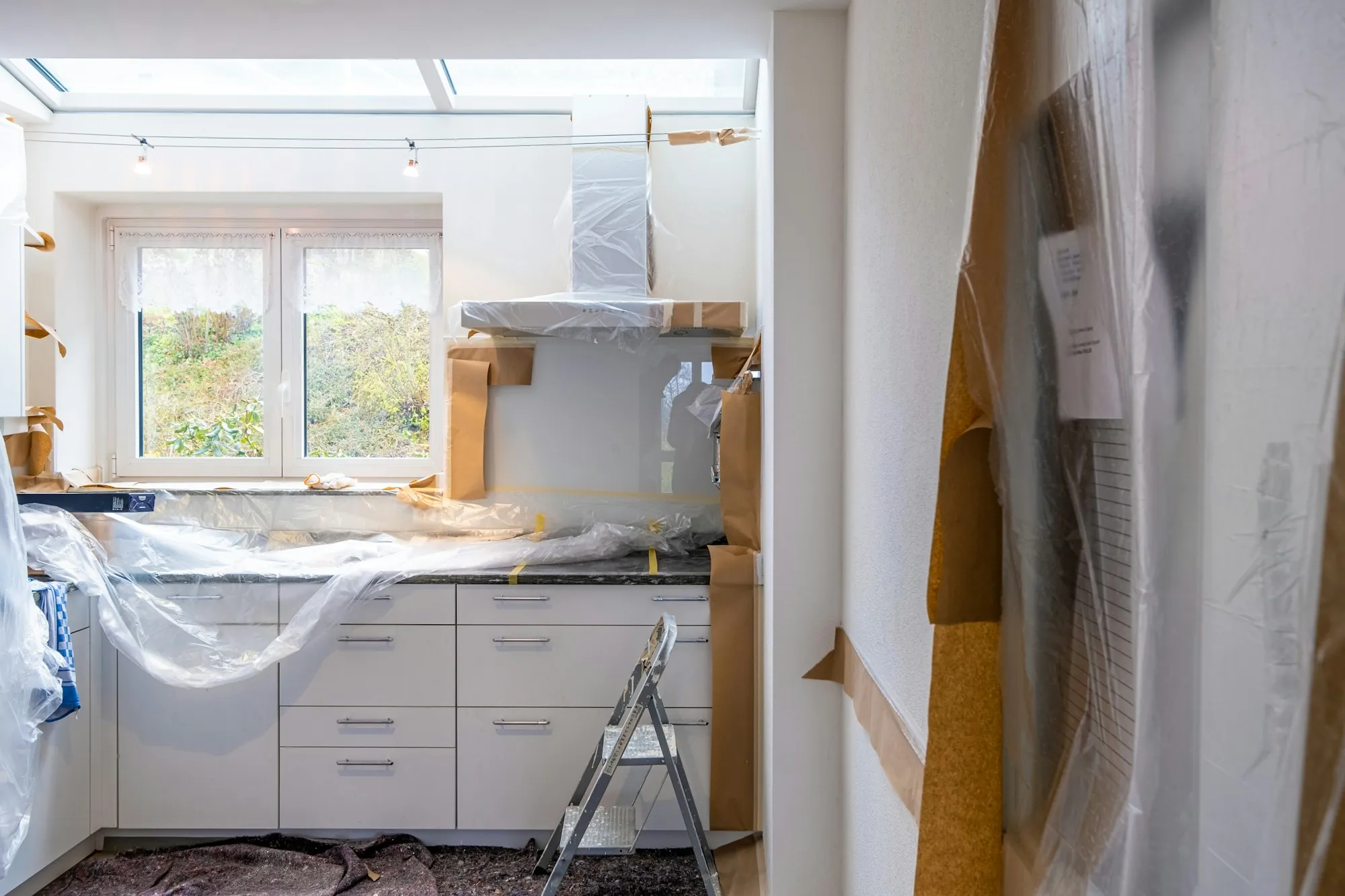 A kitchen mid-renovation with cabinets covered in protective sheeting